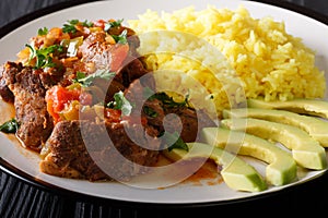 Seco de chivoÂ is goat stew with yellow rice and avocado close-up on a plate. horizontal